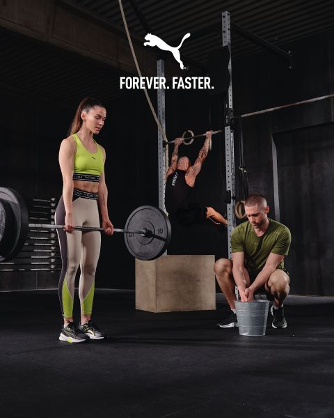 Una mujer en ropa deportiva levanta una pesa, un hombre se agacha con un cubo a su lado, otra persona cuelga de unas anillas en un gimnasio. Arriba está el texto "FOREVER. FASTER." con un logo de Puma.