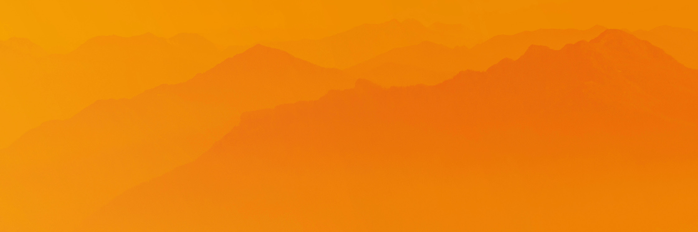 Die Silhouetten der Bergketten verschwinden in der Ferne unter einem warmen, orangefarbenen Himmel mit Farbverlauf und schaffen eine ruhige und heitere Landschaft.