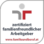 Logotipo con figuras abstractas rojas y grises junto al texto "empleador certificado como familiarmente amigable" y el sitio web "www.familieundberuf.at" debajo.