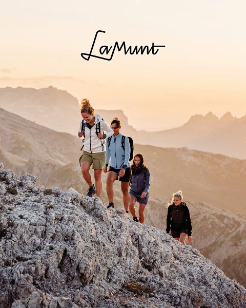 Tres personas con ropa de invierno esquían bajo un cielo despejado a través de un paisaje montañoso nevado. El texto dice: "LaMunt MOUNTAIN ME-TIME". En el fondo se ven picos nevados.