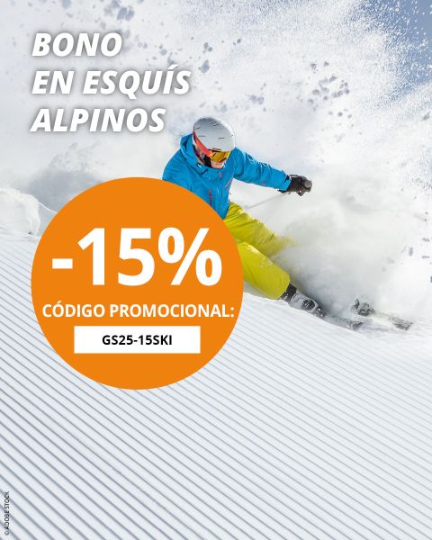 Un esquiador con chaqueta azul y pantalones amarillos desciende rápidamente por una pista nevada. Texto ofrece un 15 % de descuento en pases de esquí alpino con el código promocional GS25-15SKI.