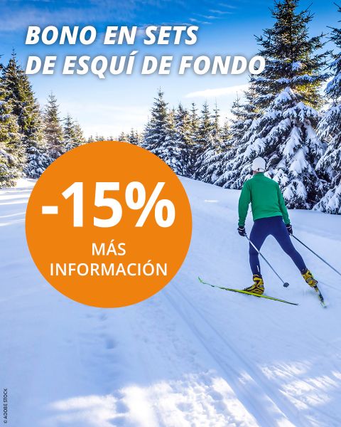 Una persona practicando esquí de fondo en una pista nevada entre pinos bajo un cielo azul. Un círculo naranja ofrece "-15%" con el código promocional "GS21-15SETLANGLAUF" para sets de esquí de fondo en texto español y alemán.