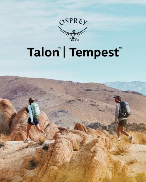 Una persona desciende un terreno rocoso con una mochila verde, un gorro negro y ropa oscura. La luz del sol ilumina el paisaje. En primer plano se ve el logo de Osprey.