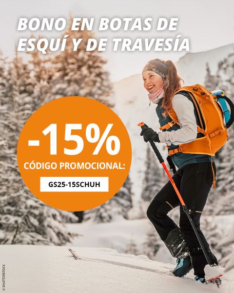 Una mujer esquía cuesta arriba entre árboles nevados, sonriendo y vestida con ropa de invierno con una mochila naranja. Un círculo naranja en la imagen ofrece un código promocional de "-15% código promocional: GS25-15SCHUH" de descuento en botas de esquí y de travesía.