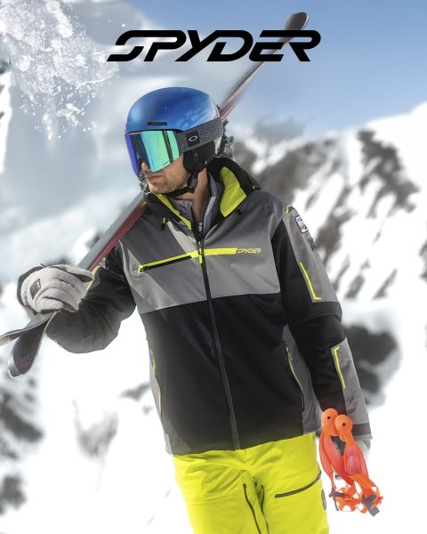 Un esquiador con un traje negro y amarillo baja por una ladera nevada, con un paisaje nevado al fondo. En la parte superior está el texto: "SPYDER PARA ESQUIADORES DESDE 1978". En la esquina inferior derecha hay un pequeño logotipo blanco de una araña.