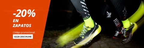 Dos personas corriendo de noche con zapatillas deportivas negras y calcetines de color amarillo neón; en el texto se ofrece un descuento del 20 % en zapatos con el código promocional GS26-20$ZAPATOS.