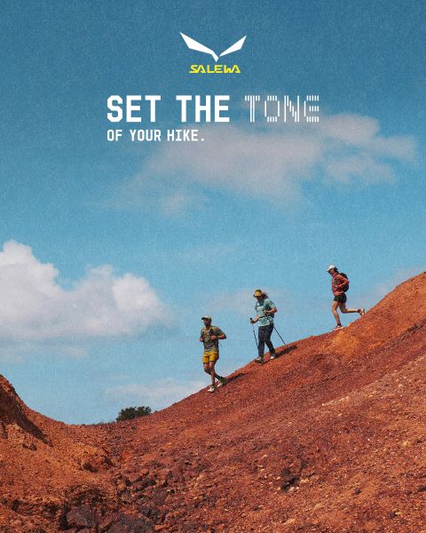 Una persona con chaqueta blanca y gafas de sol escala un terreno rocoso. El efecto de desenfoque de movimiento enfatiza la velocidad y el movimiento. Arriba está el texto "MXT Forward A Fast Story", a la derecha el logo de Salewa.