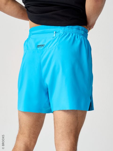 Persona con pantalones deportivos azul claro y una parte de arriba negra, fotografiada desde atrás delante de un fondo claro.