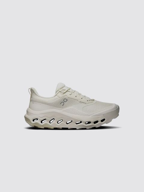 Una zapatilla gris con detalles en negro, suela blanca y un distintivo logo "V" negro en el lateral. La palabra "ZAPATILLA" aparece en negrita y en blanco en la parte superior izquierda sobre un fondo gris claro.