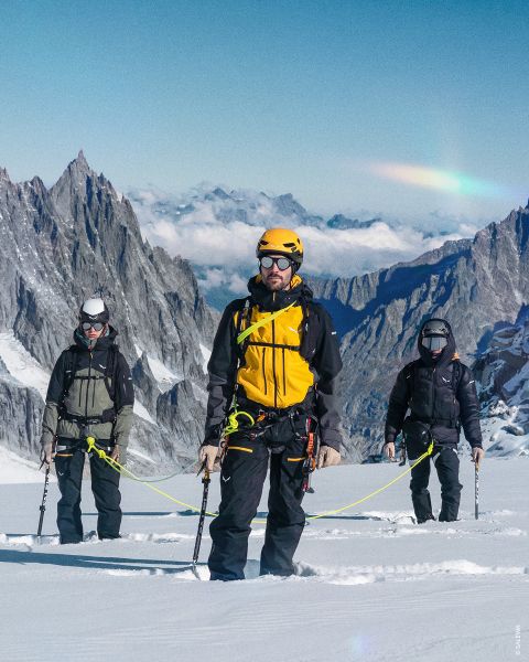 Dos imágenes sobre un fondo rocoso. Izquierda: Mujer en ropa de senderismo púrpura con casco. Derecha: Persona en ropa verde y azul con mochila amarilla, equipo de escalada y cuerda enrollada. Texto: "TIPO OUTDOOR ALPINISTA".