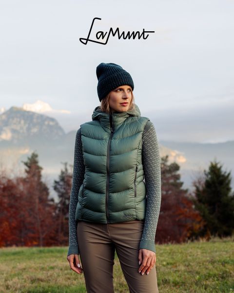 Tres personas con ropa de invierno esquían bajo un cielo despejado a través de un paisaje montañoso nevado. El texto dice: "LaMunt MOUNTAIN ME-TIME". En el fondo se ven picos nevados.