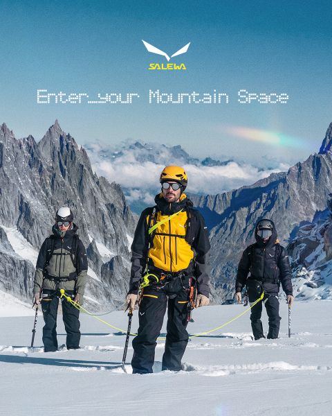 Una persona con chaqueta blanca y gafas de sol escala un terreno rocoso. El efecto de desenfoque de movimiento enfatiza la velocidad y el movimiento. Arriba está el texto "MXT Forward A Fast Story", a la derecha el logo de Salewa.