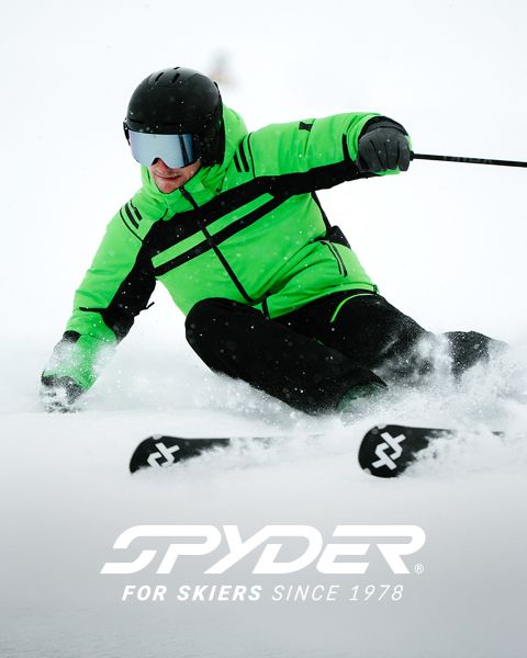 Un esquiador con un traje negro y amarillo baja por una ladera nevada, con un paisaje nevado al fondo. En la parte superior está el texto: "SPYDER PARA ESQUIADORES DESDE 1978". En la esquina inferior derecha hay un pequeño logotipo blanco de una araña.